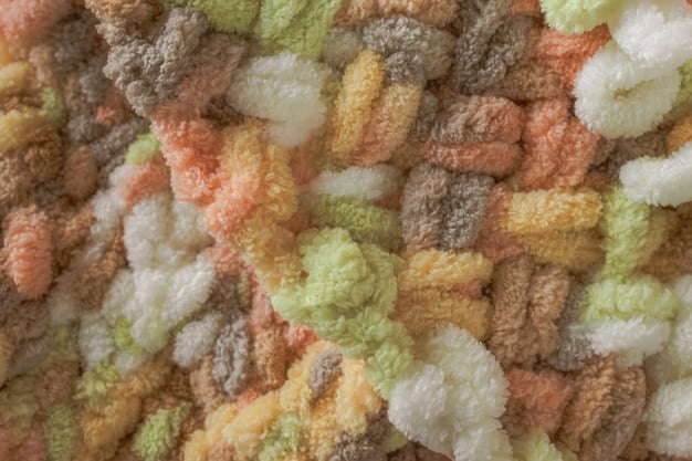 A close-up of different textures of boucle wool, showing the looped and curly fibers in various neutral and pastel colors.
