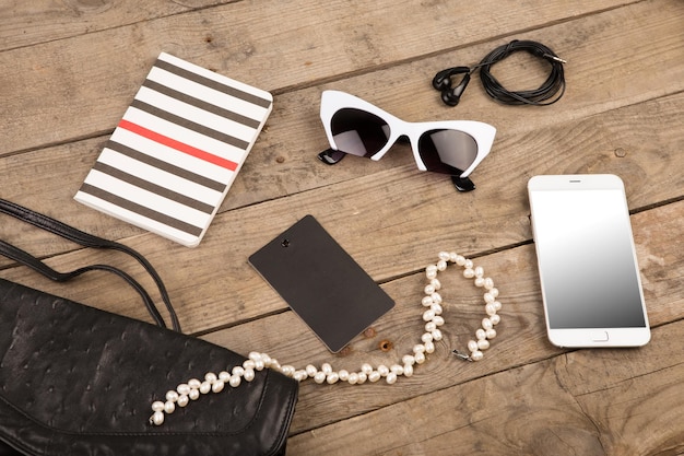 A close-up shot of various fashion accessories laid out on a table, including jewelry, a handbag, sunglasses, and a scarf. The accessories are arranged to show different styles and textures.