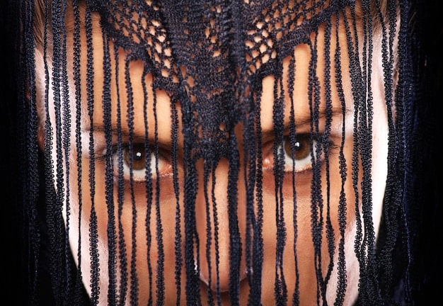 A close-up shot of a model wearing an avant-garde outfit with intricate patterns and textures at Paris Fashion Week. The focus is on the detail of the garment and the model's expression.