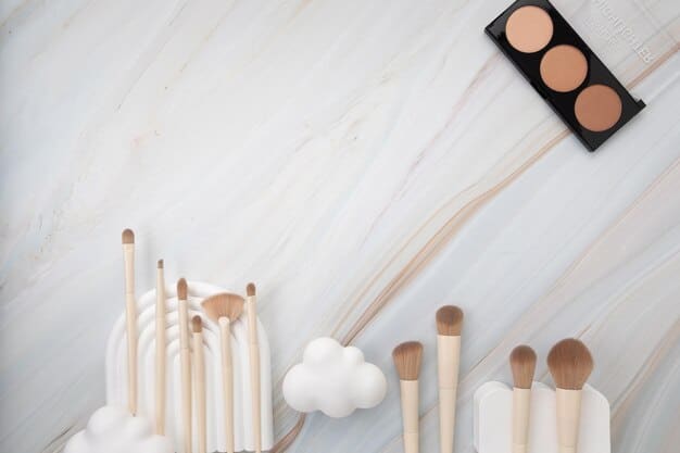 A flat lay of essential nude makeup tools arranged on a white marble surface. This includes a foundation brush, concealer brush, blush brush, eyeshadow blending brush, and a brow spoolie. The tools are high-quality with sleek designs.