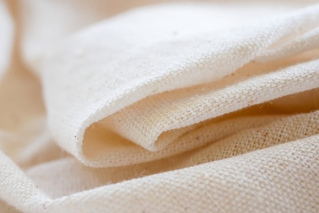 A close-up shot of organic cotton fabric, showcasing its soft texture and natural color. A hand gently touching the fabric to emphasize its softness.