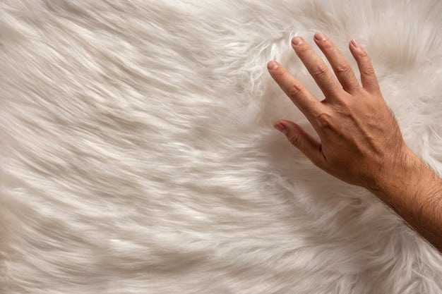 Extreme close-up of soft merino wool texture. A hand gently touching the merino wool, highlighting its delicate and luxurious texture.