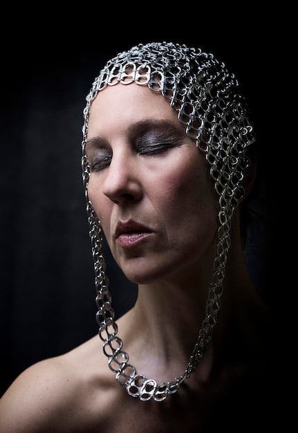A close-up shot of a model wearing large, sculptural earrings and layered necklaces. The jewelry is metallic and features geometric shapes, symbolizing modern elegance and boldness.