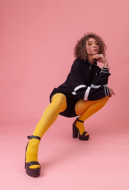 A stylish woman is photographed from the knees down, showcasing her trendy shoes. She is wearing chunky platform sandals in a bold color, paired with fashionable socks and cropped trousers.