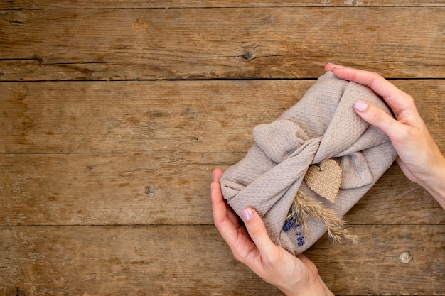 A close-up shot of a woman's hand holding a piece of clothing made of brightly colored linen, with natural light highlighting the fabric's texture.