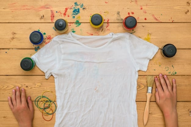 A pair of hands using fabric markers to draw a custom design on a plain white t-shirt. The t-shirt is laid flat on a table covered with colorful fabric scraps and other art supplies.