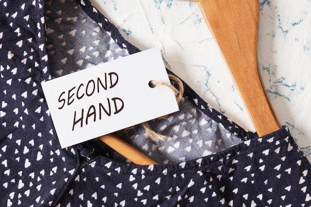 A close-up photo of a price tag on a Shein garment, with a handwritten resale price above it. The image focuses on the decision-making process behind setting a fair price for reselling clothes.