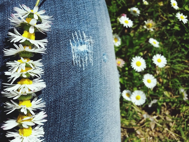 A collage of close-up shots showing different DIY jean customization techniques, including embroidered floral patterns, distressed denim with patches, painted abstract designs, and embellished pockets with beads and sequins, all on various shades of blue denim.