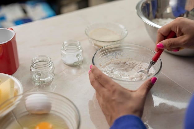 A person mixing baking soda with water in a small bowl, preparing a paste for cleaning shoes. The focus is on the mixture and the texture of the paste.