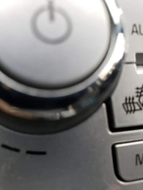 A close-up of a washing machine dial set to a low spin speed, with a hand adjusting it. The scene is well-lit and the focus is on the control panel and the symbol for gentle spin.