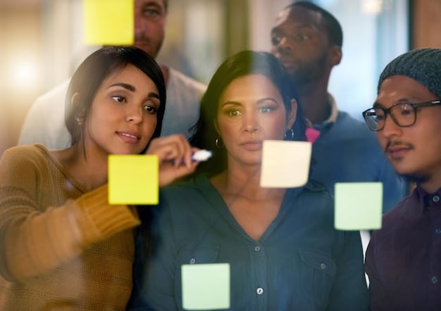 A diverse group of interns brainstorming ideas around a table in a brightly lit office, using sticky notes and laptops, showing collaboration and innovation.