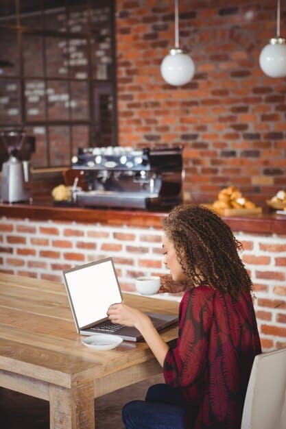 A person using a laptop while sitting in a coffee shop, focused on an online course or webinar, representing flexible and accessible learning opportunities.