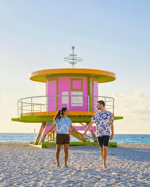 A panoramic beach scene at sunset, showcasing people in vibrant summer outfits in colors like coral, turquoise, and lemon yellow. Focus on the interplay of light and color, capturing the essence of summer fun and energy.