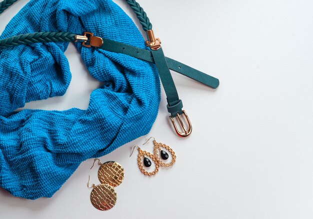 A close-up shot of various accessories laid out on a table, including a statement necklace, a silk scarf, a pair of elegant earrings, and a clutch purse.
