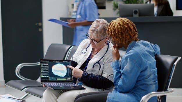 A doctor examining a patient wearing a smart shirt that wirelessly transmits vital signs data to a computer, illustrating the use of wearable technology in healthcare.