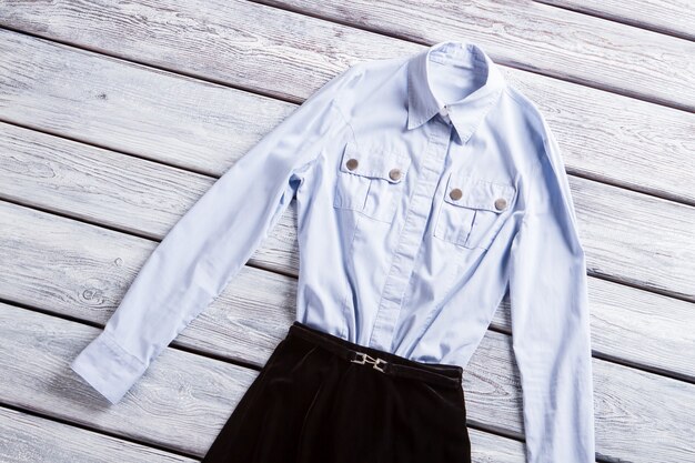 A close-up shot of various Shein workwear items, including a crisp white button-down shirt, a black pencil skirt, and a navy blue cardigan, neatly arranged on a light-colored background.