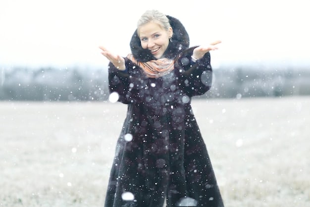 A person wearing a Shein winter coat standing in light snow, with water droplets visible on the coat's surface, demonstrating its water resistance.