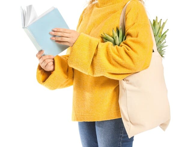 A woman carrying a large Shein tote bag filled with books, a laptop, and a water bottle, walking through a bustling city street. The tote bag is stylish and functional, complementing her casual outfit.