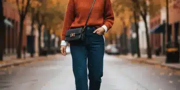 Woman in stylish SHEIN fall outfit, layering knit sweater over white shirt with jeans and ankle boots.